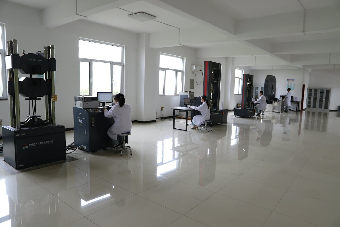 Tecnici che utilizzano macchine industriali per test sui materiali in un laboratorio moderno.